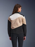 Chaqueta Alpinestars Stella Moshell, chaqueta de moto urbana para mujer, negro, arena y blanco roto, vista posterior en una modelo, diseño asimétrico de bloques de color con un gran gráfico en la espalda, equipo de protección de inspiración urbana moderna