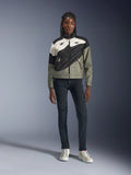 Chaqueta Alpinestars Stella Moshell para mujer, en color negro, gris y blanco roto con detalles en rosa, lucida por una modelo con vaqueros oscuros y zapatillas blancas, con diseño de cremallera asimétrica y gráficos geométricos llamativos, equipamiento urbano contemporáneo