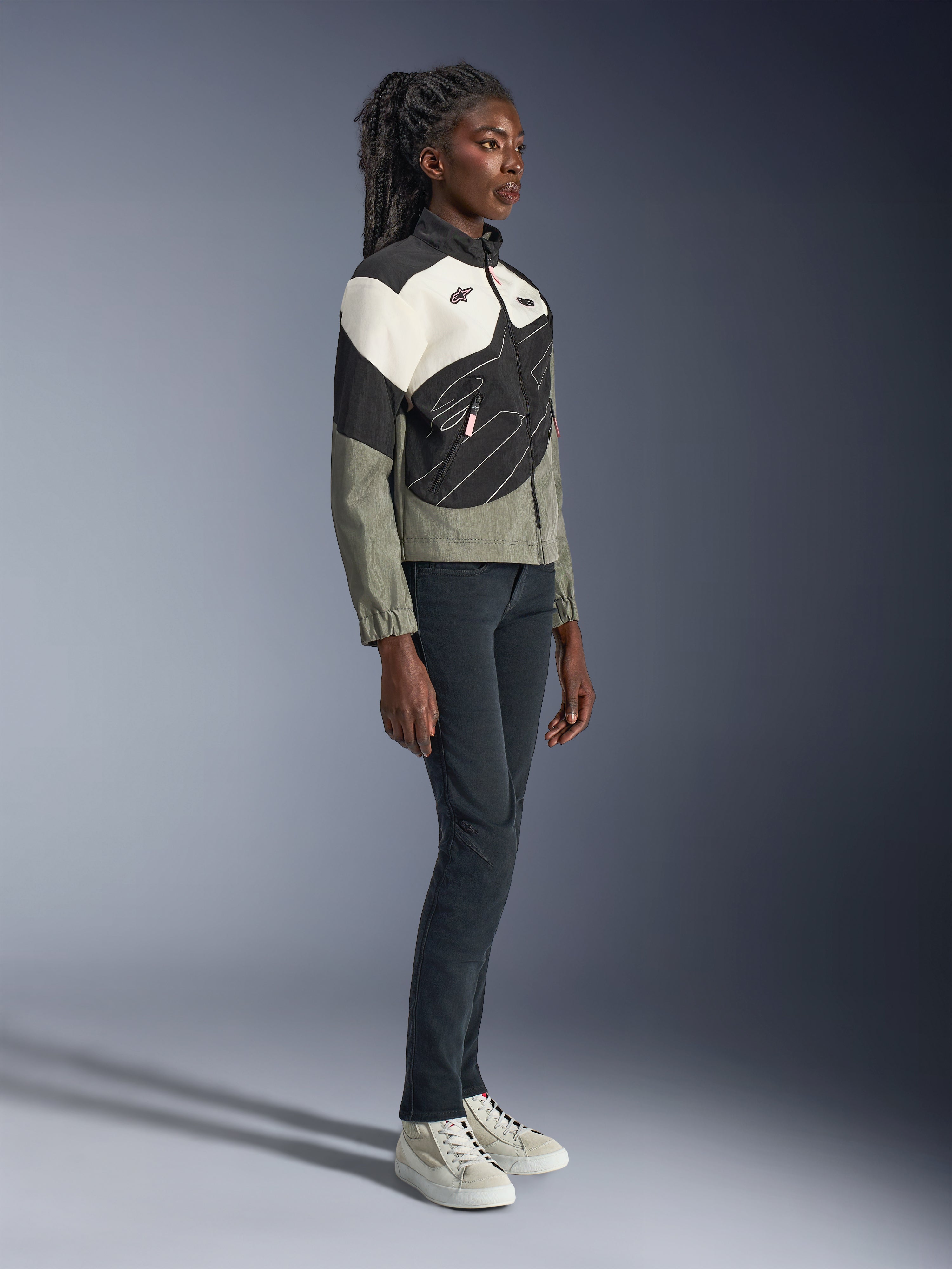 Chaqueta Alpinestars Stella Moshell, chaqueta de moto urbana para mujer, gris, negra y blanco roto con detalles rosas, vista de cuerpo completo de una modelo con pantalones oscuros y zapatillas, diseño contemporáneo inspirado en el estilo streetwear para la conducción urbana