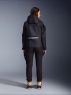 Pantalones Alpinestars Actea para mujer, pantalones de moto negros con un ajuste entallado, combinados con una chaqueta oscura Molly Air con capucha y botas color canela, vista posterior de una motorista con equipamiento de motociclismo urbano