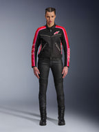 Mujer motociclista con la chaqueta Alpinestars Stella T-Dyno Air, negra con detalles en rojo brillante y fucsia, combinada con pantalones de moto negros y botas con cordones, con paneles de malla 3D, ajuste entallado y logotipos de estrellas rosas, conjunto de equipamiento para conducción urbana