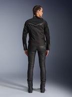 Chaqueta Alpinestars Stella T-Dyno Air, vista trasera, chaqueta de moto negra para mujer con ribetes blancos y un pequeño logotipo de estrella, usada con pantalones técnicos negros y botas de motorista, ajuste elegante de motociclista para conducción urbana