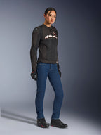 Chaqueta Alpinestars Stella SMX Air, chaqueta de moto textil para mujer, negra con detalles blancos y rojos, combinada con vaqueros azules, guantes negros y calzado de moto negro, equipamiento de conducción urbana deportiva para mujer.