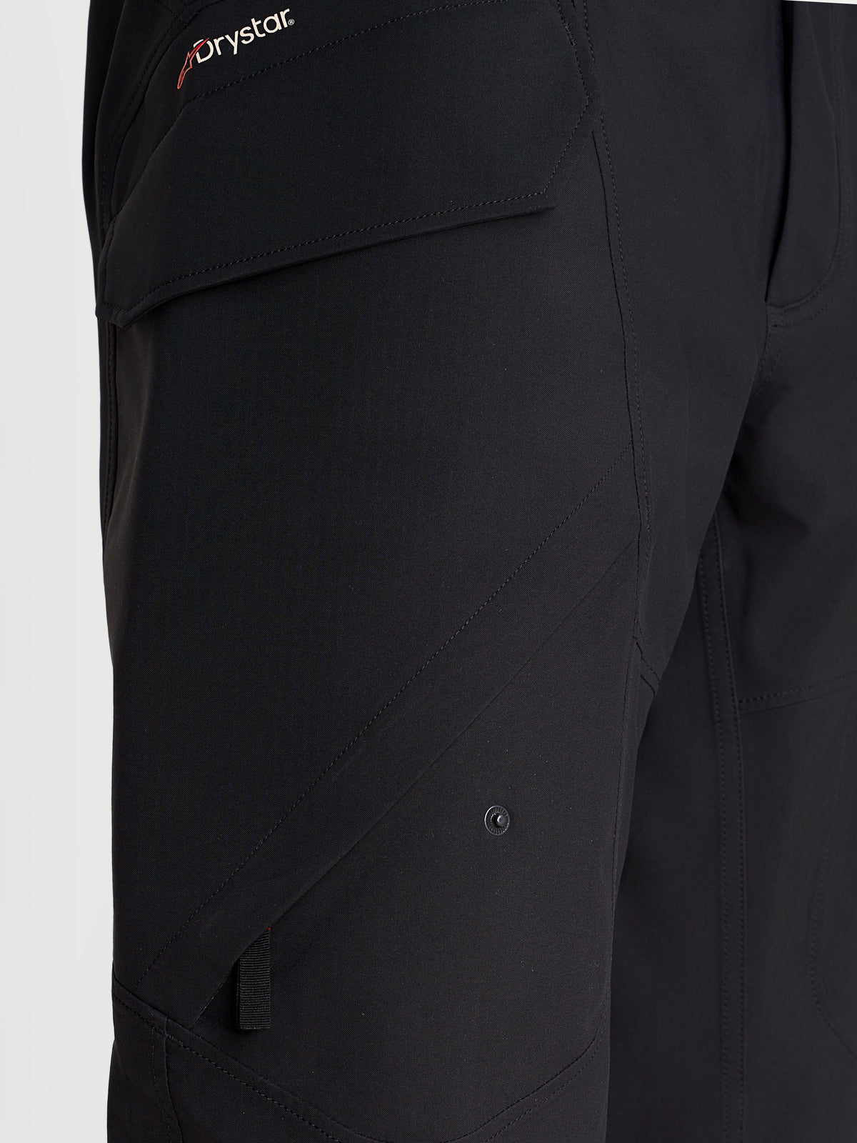 Alpinestars Juggernaut V2 Drystar Pantalones, pantalones de moto urbanos impermeables para hombre, en negro, vista de primer plano que destaca el bolsillo cargo lateral y la marca Drystar