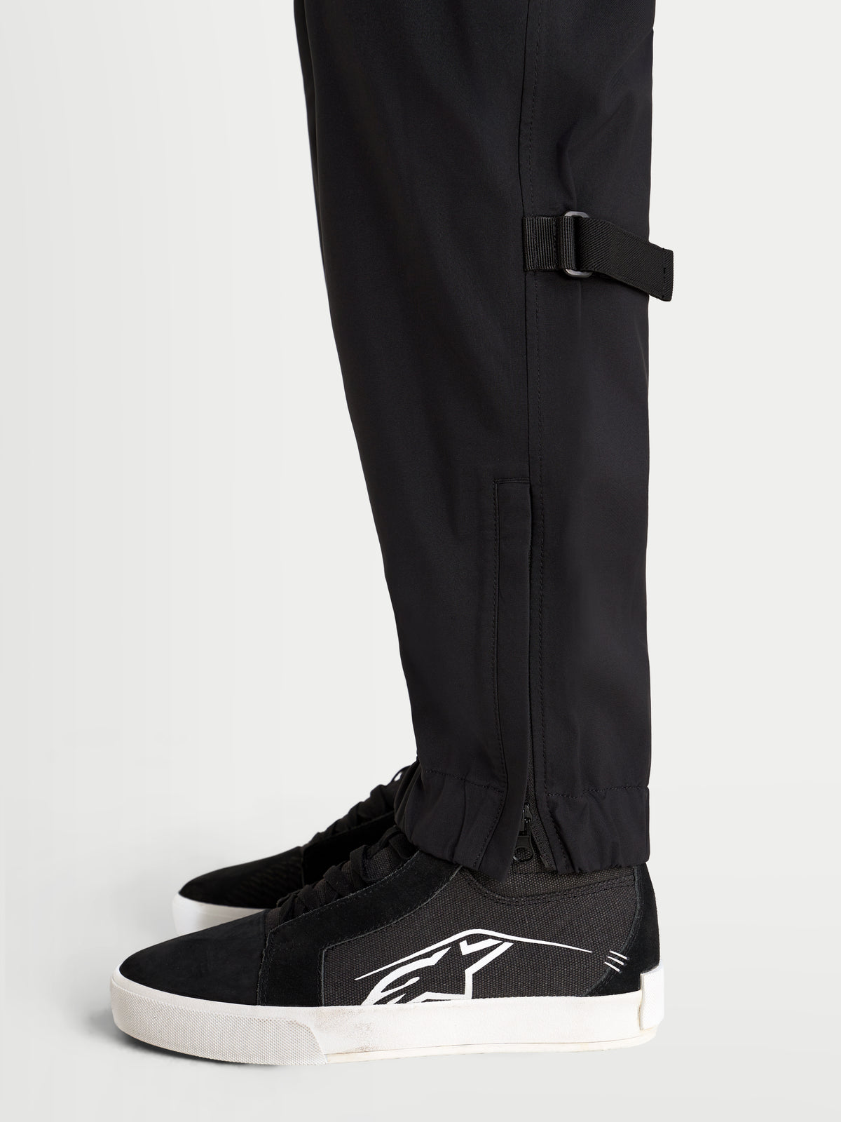 Alpinestars Juggernaut V 2 Drystar Pantalones, pantalones de moto urbanos para hombre, negros, vista lateral en primer plano que muestra el ajuste en la pantorrilla y el dobladillo elástico con abertura con cremallera en modelo