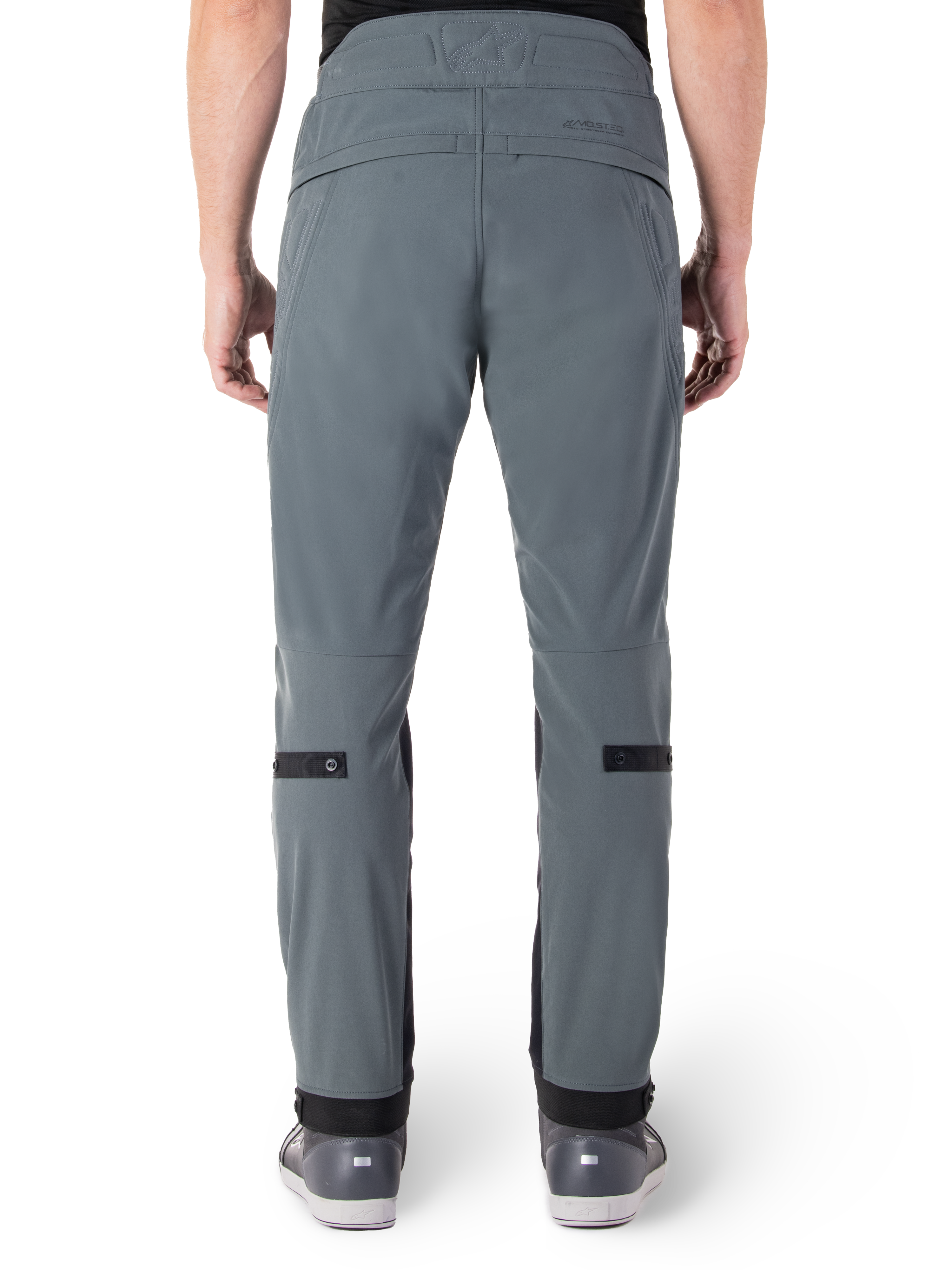 Alpinestars Alden Pants, Urban Gray, vista trasera de pantalones de moto urbanos para hombre, corte ajustado bajo la rodilla con correas de ajuste negras en las pantorrillas, diseño de cintura alta con el logotipo MO.ST.EQ. en el canesú trasero, usados con calzado de conducción gris