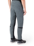 Pantalones Alpinestars Alden, Gris Urbano, vista lateral trasera, pantalones técnicos de conducción inspirados en el estilo urbano con detalles acolchados en la cintura y correas negras en la pantorrilla, combinados con calzado de conducción gris, equipamiento de motociclismo urbano moderno