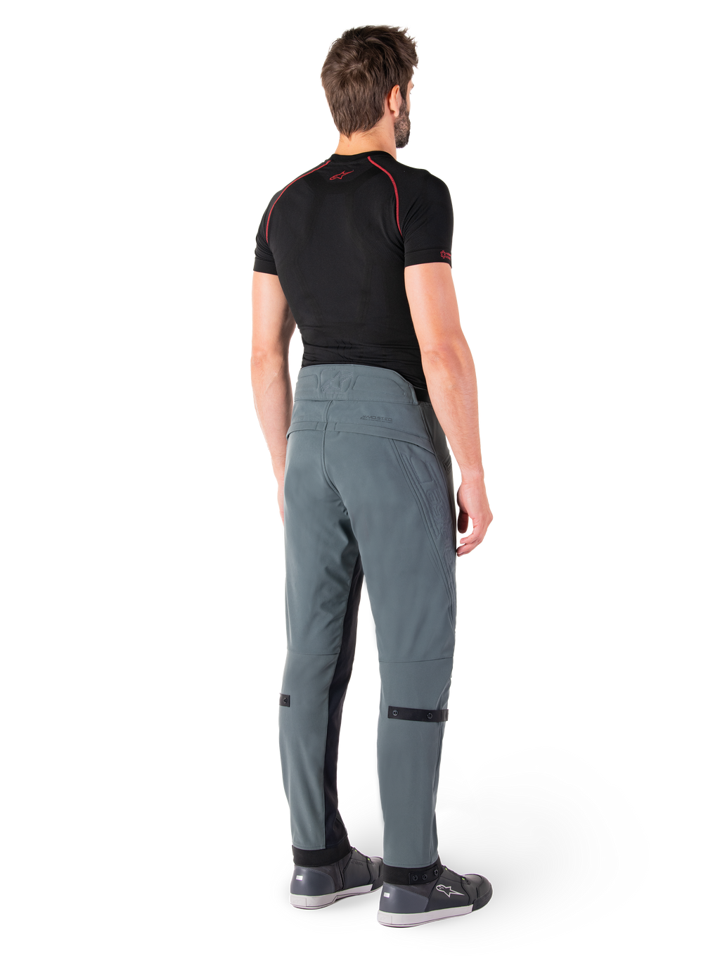 Pantalones Alpinestars Alden, Urban Gray, vista trasera, pantalones de moto de tejido técnico con detalles acolchados en la parte superior trasera de la cintura y las piernas, combinados con una capa base negra y calzado de conducción gris, estilo streetwear urbano contemporáneo.