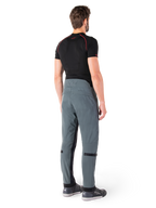 Pantalones Alpinestars Alden, Urban Gray, vista trasera, pantalones de moto de tejido técnico con detalles acolchados en la parte superior trasera de la cintura y las piernas, combinados con una capa base negra y calzado de conducción gris, estilo streetwear urbano contemporáneo.