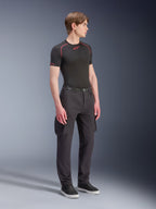 Alpinestars Flex-AST Cargo Pants, negros, pantalones de moto urbanos con bolsillos cargo y dobladillos elásticos, lucidos por un modelo con una capa base negra de manga corta y zapatillas, diseño moderno ahusado