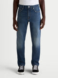 Alpinestars Flex-AST 8 Denim Pantalones, pantalones de moto urbanos para hombre en azul medio, vista frontal en modelo con zapatillas casuales, denim monocapa certificado CE con características protectoras