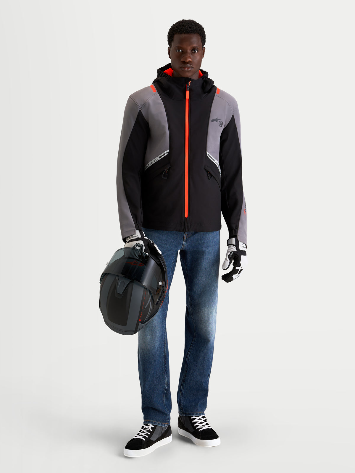 Alpinestars Flex Ast 8 Denim Pantalones, pantalones de moto urbanos para hombre en azul medio, con un modelo que sostiene un casco y viste chaqueta técnica negra y gris