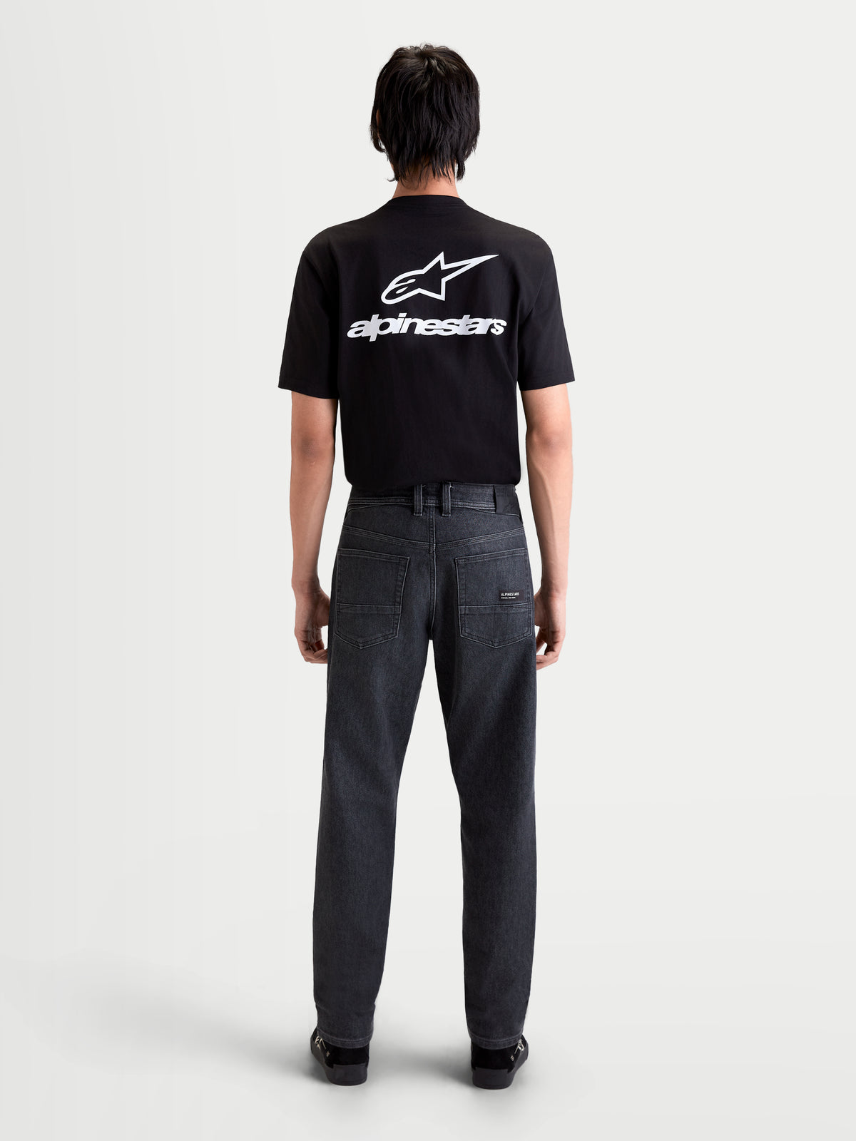 Alpinestars Flex-AST 7 Denim Pantalones, pantalones de moto urbanos para hombre en negro descolorido, vista trasera que muestra denim técnico de una sola capa, diseño de cinco bolsillos y parche de cuero en modelo