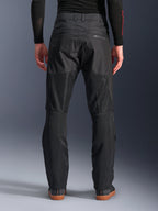 Pantalones Alpinestars C-1 Air, vista trasera, negros, pantalones urbanos de moto fabricados en tejido textil con amplios paneles de malla técnica en la parte posterior de las piernas para mayor ventilación, diseño limpio con marca sutil, combinados con una capa base negra y calzado casual para conducir.