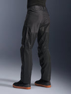 Alpinestars C-1 Air Pants, pantalones urbanos de moto, color negro, vista trasera que muestra grandes paneles de malla técnica en la parte posterior de las piernas para ventilación, estilo limpio para conducción urbana, combinados con zapatillas casuales negras.
