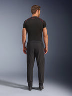 Pantalones Alpinestars Aeroshell Airflow, pantalones de motociclismo negros, vista posterior mostrada en un modelo con una capa base negra y botas, con un chasis de softshell ligero con paneles de malla integrados para ventilación.