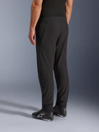 Alpinestars Aeroshell Airflow Pants, pantalones de moto negros, vista trasera en tres cuartos, construcción de softshell elástico ligero con paneles de malla integrados, puños de tobillo ajustables, usados con calzado de conducción Alpinestars negro