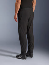 Alpinestars Aeroshell Airflow Pants, Black Motorcycle Pants, three-quarter rear view, lightweight stretch softshell construction with integrated mesh panels, adjustable ankle cuffs, worn with black Alpinestars riding shoes