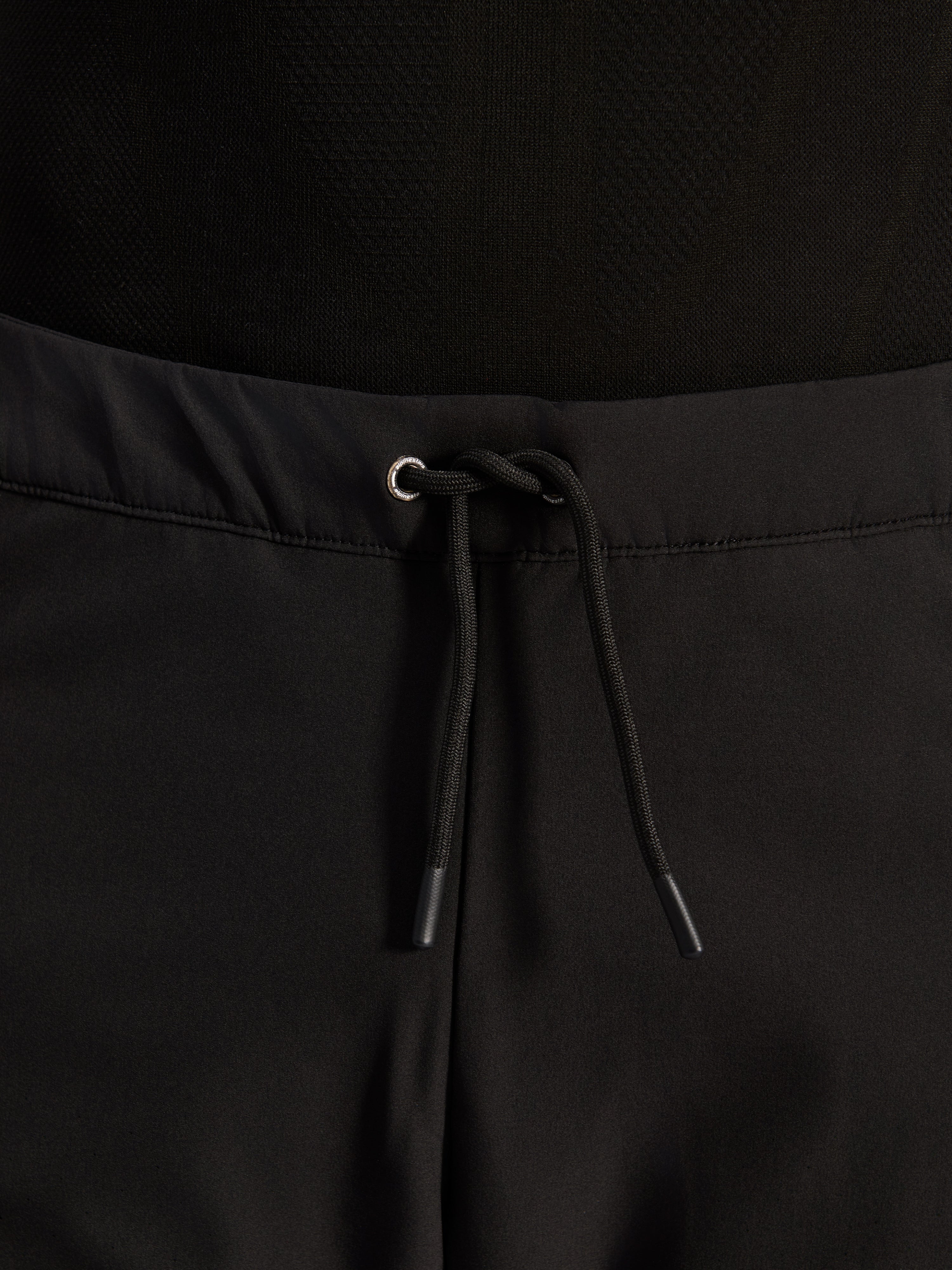 Alpinestars Aeroshell Airflow Pants, negros, primer plano de la cintura con cordón elástico interno ajustable y detalle de ojal plateado, equipamiento de motociclismo sport-touring