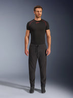 Modelo luciendo los pantalones Alpinestars Aeroshell Airflow en color negro, combinados con una prenda técnica de manga corta negra y botas de moto negras. Estos pantalones de moto ligeros de softshell cuentan con cintura con cordón y puños elásticos, diseñados para pilotos de sport y touring en condiciones de clima cálido.
