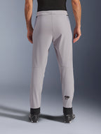 Pantalones Alpinestars Aeroshell Airflow, pantalones de moto, Mid Gray, vista trasera que muestra las zonas perforadas con láser en las pantorrillas y el logotipo negro de Astars, confección en softshell textil con puños negros en los tobillos y paneles de malla en la cadera.