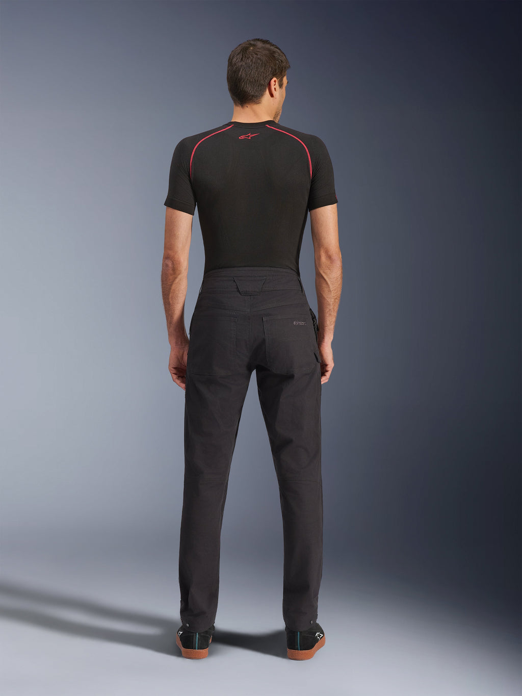 Alpinestars Flex-AST Canvas Pants, Urban Motorcycle Pants, Black, Rear view showing workwear-inspired design with back pockets and extended back rise, worn with a black base layer and sneakers, ergonomic ride fit