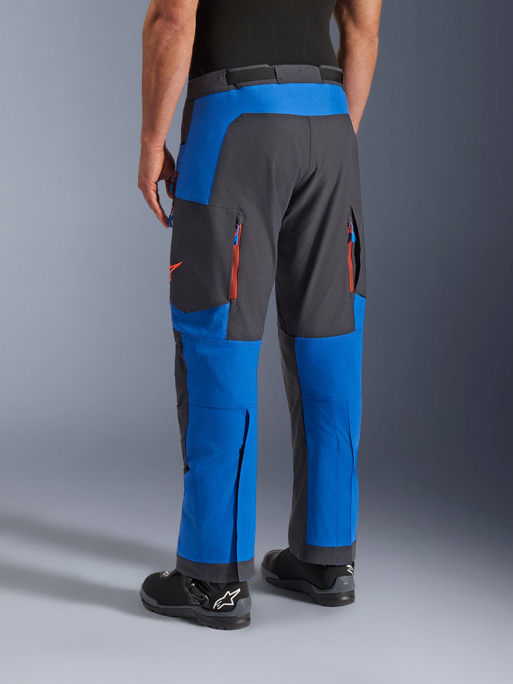 Alpinestars Maxdura Dual Pants, azul real y gris oscuro, vista trasera que muestra bolsillos con cremallera y zonas de ventilación, diseño sobre la bota usado con botas Alpinestars negras, equipamiento duradero para conducción de aventura y dual-sport