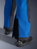 Pantalones Alpinestars Maxdura Dual, azul real y gris oscuro, primer plano de la parte inferior ajustable con cierres de presión y fuelle, diseño de ajuste de aventura sobre la bota, usados con botas de motocicleta Alpinestars negras