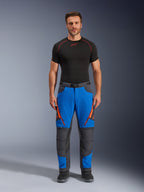 Alpinestars Maxdura Dual Pants, pantalones de moto de aventura, azul real y gris oscuro, detalles de cremalleras naranjas, usados con una capa base Alpinestars negra y botas negras, con paneles reforzados en las rodillas y un diseño técnico off-road