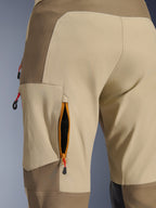 Pantalones Alpinestars Maxdura Dual en Walnut Aluminum, detalle de la abertura de ventilación con cremallera en el muslo con ribete naranja y malla negra, tejido de poliamida elástica de alta resistencia en tonos canela y marrón con tiradores rojos