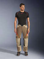 Alpinestars Maxdura Dual Pants, pantalones de conducción Adventure y Dual-Sport, Walnut Aluminum, usados con una camiseta de compresión negra de manga corta y botas de adventure, con ventilaciones con cremallera naranja y logos rojos en los muslos, cinturón negro con hebilla, diseño sobre la bota para conducción de motocicletas.