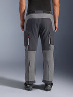 Pantalones Alpinestars Maxdura Dual, pantalones de aventura para moto, gris oscuro y gris intenso, vista trasera que resalta los paneles reforzados en el asiento y las rodillas, ventilaciones con cremallera en los muslos, usados con botas Alpinestars negras, construcción de poliamida elástica de alta resistencia para conducción dual-sport.