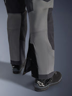 Pantalones Alpinestars Maxdura Dual, pantalones de motociclismo de aventura, gris oscuro y gris intenso, vista de cerca del dobladillo ajustable sobre la bota con cierres a presión y paneles reforzados, usados con botas Alpinestars negras, diseño técnico robusto para conducción dual-sport