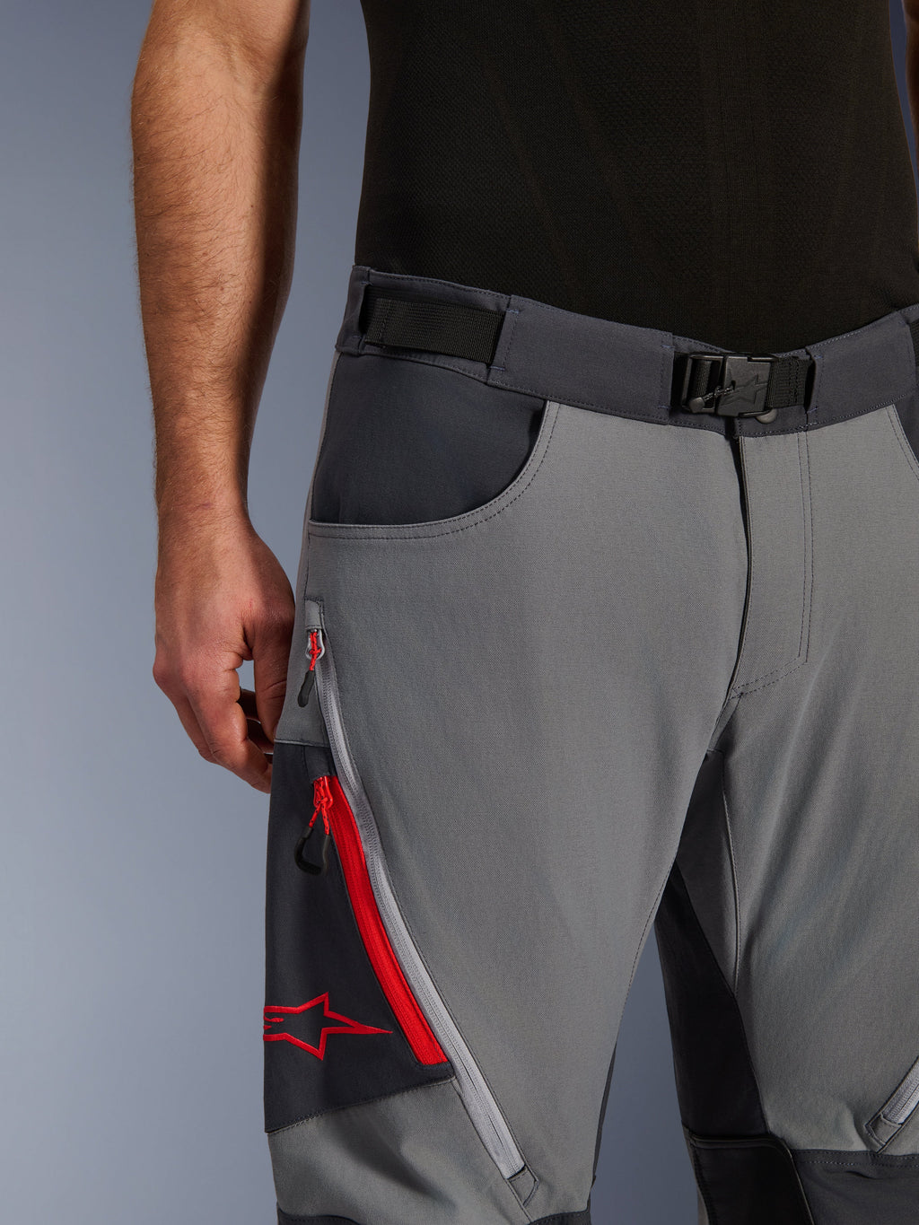 Pantalones Alpinestars Maxdura Dual, pantalones de motociclismo de aventura, gris oscuro y gris intenso, primer plano con cinturón ajustable con hebilla magnética, bolsillo de carga con cremallera con detalles rojos y logotipo de Alpinestars