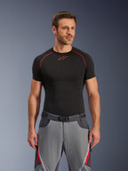 Pantalones Alpinestars Maxdura Dual, gris oscuro y gris intenso con detalles en rojo, combinados con una camiseta de capa base negra con costuras rojas, ajuste atlético con cinturón de hebilla magnética integrado, equipamiento duradero para motociclismo de aventura