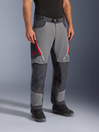 Pantalones Alpinestars Maxdura Dual en gris oscuro y gris intenso, pantalones de motociclismo adventure-touring con ventilaciones con cremallera roja en los muslos y logo de estrella, paneles oscuros reforzados en las rodillas, combinados con botas de motociclismo negras