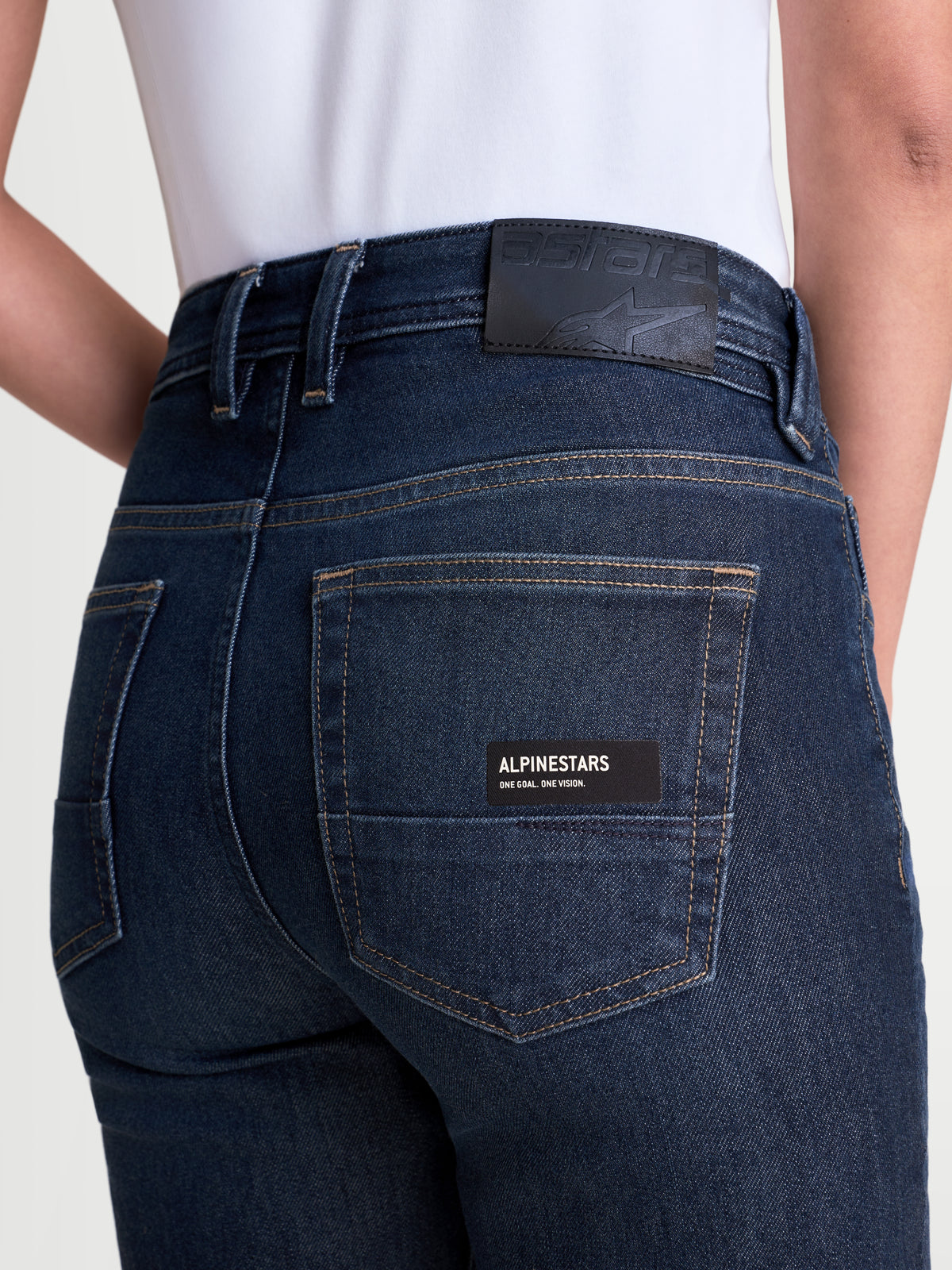 Alpinestars Stella Flex-AST 7 Denim Pants, women's urban motorcycle riding jeans, dark blue, rear close-up view showing leather back patch, branded pocket label, and single-layer technical denim construction worn by a model