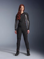 Alpinestars Stella Troop-Air Pants, pantalones de moto para mujer en color negro, incluye paneles de malla y bolsillos con cremallera, combinados con una chaqueta de malla negra y gris con detalles rosas y botas de moto negras, conjunto completo de motociclismo urbano