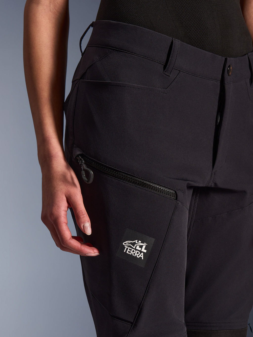 Pantalones Alpinestars Stella Flex-AST Explorer para mujer, negros, primer plano que muestra el bolsillo con cremallera en el muslo y el parche de marca ALL TERRA, textil elástico ligero para conducción de aventura