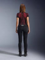 Alpinestars Daisy V3 Women's Riding Denim, Rinse Black, pantalones de moto de corte ajustado vistos desde atrás, con diseño de cintura alta y bolsillos traseros, combinados con una camiseta técnica con estampado en rojo y negro y botas negras, equipamiento de moto urbano para mujer