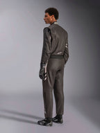 Alpinestars GP Race V3 Suit FIA, mono de automovilismo negro con detalles plateados, visto desde una perspectiva trasera de tres cuartos en un modelo, combinado con guantes y botas de carreras negros a juego, equipamiento profesional de automovilismo con un diseño de dos capas.