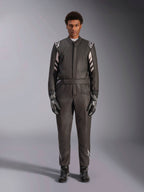 Alpinestars GP Race V3 Suit FIA, mono de automovilismo, negro y plata, vista frontal del piloto con equipamiento de carreras completo incluyendo guantes y botas, diseño profesional con logotipos de Alpinestars en hombros y cinturón