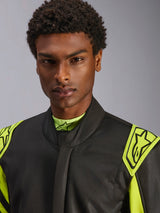 Primer plano de un modelo con el traje Alpinestars GP Race V3 FIA en negro y amarillo flúor, con hombreras de extracción amarillas con logotipos de estrella, diseño de cuello alto, equipamiento profesional para automovilismo