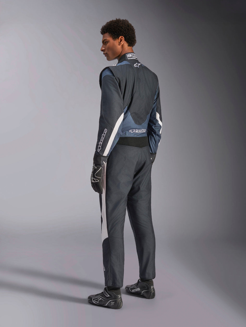 Alpinestars GP Pro Comp V2, traje de carreras de auto para hombre, negro y gris asfalto, certificado FIA, vista trasera 3/4.