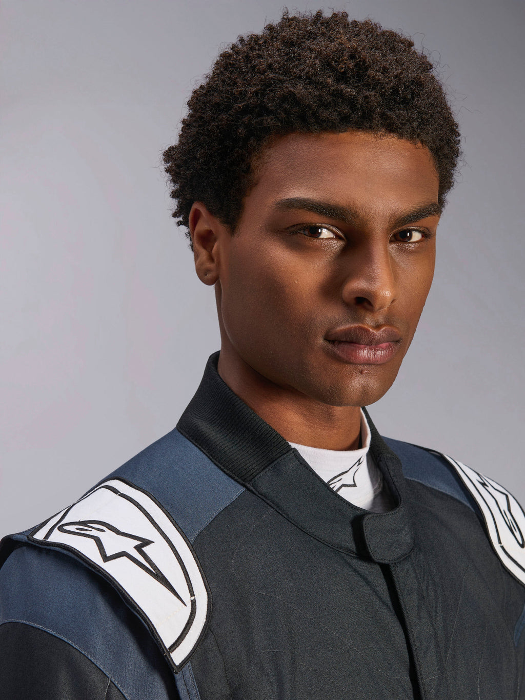 Traje Alpinestars GP Pro Comp V2 FIA, traje de carreras de auto para hombre, negro y asfalto con hombreras blancas.