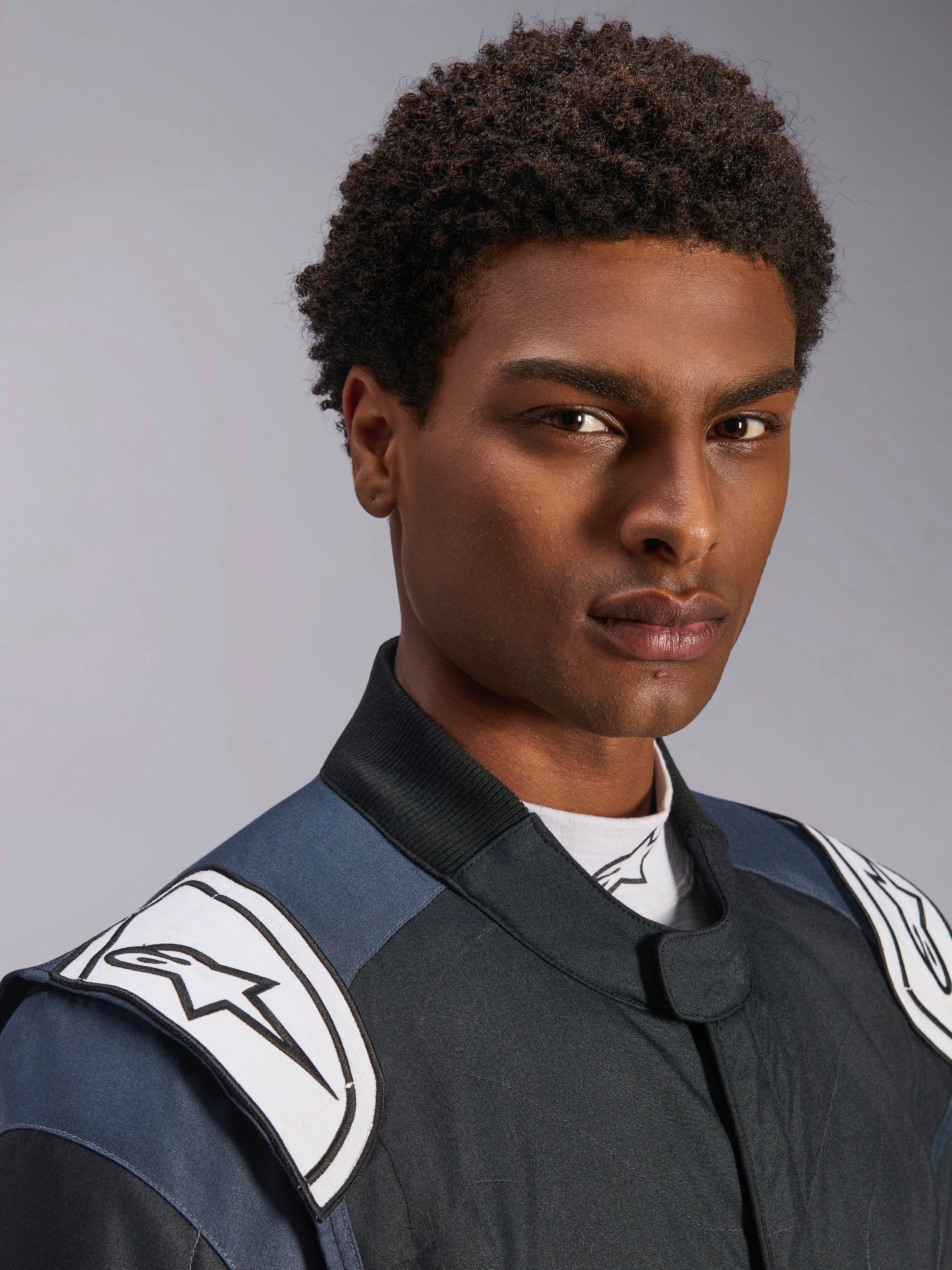 Traje Alpinestars GP Pro Comp V2 FIA, traje de carreras de auto para hombre, negro y asfalto con hombreras blancas.