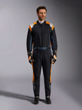 Alpinestars GP Pro Comp V2 FIA Suit, mono de carreras de automovilismo en negro asfalto y naranja flúor, modelo masculino con equipo de protección completo, guantes y calzado de carreras a juego, con logotipos blancos de Alpinestars y paneles laterales naranja vibrante, indumentaria profesional para automovilismo
