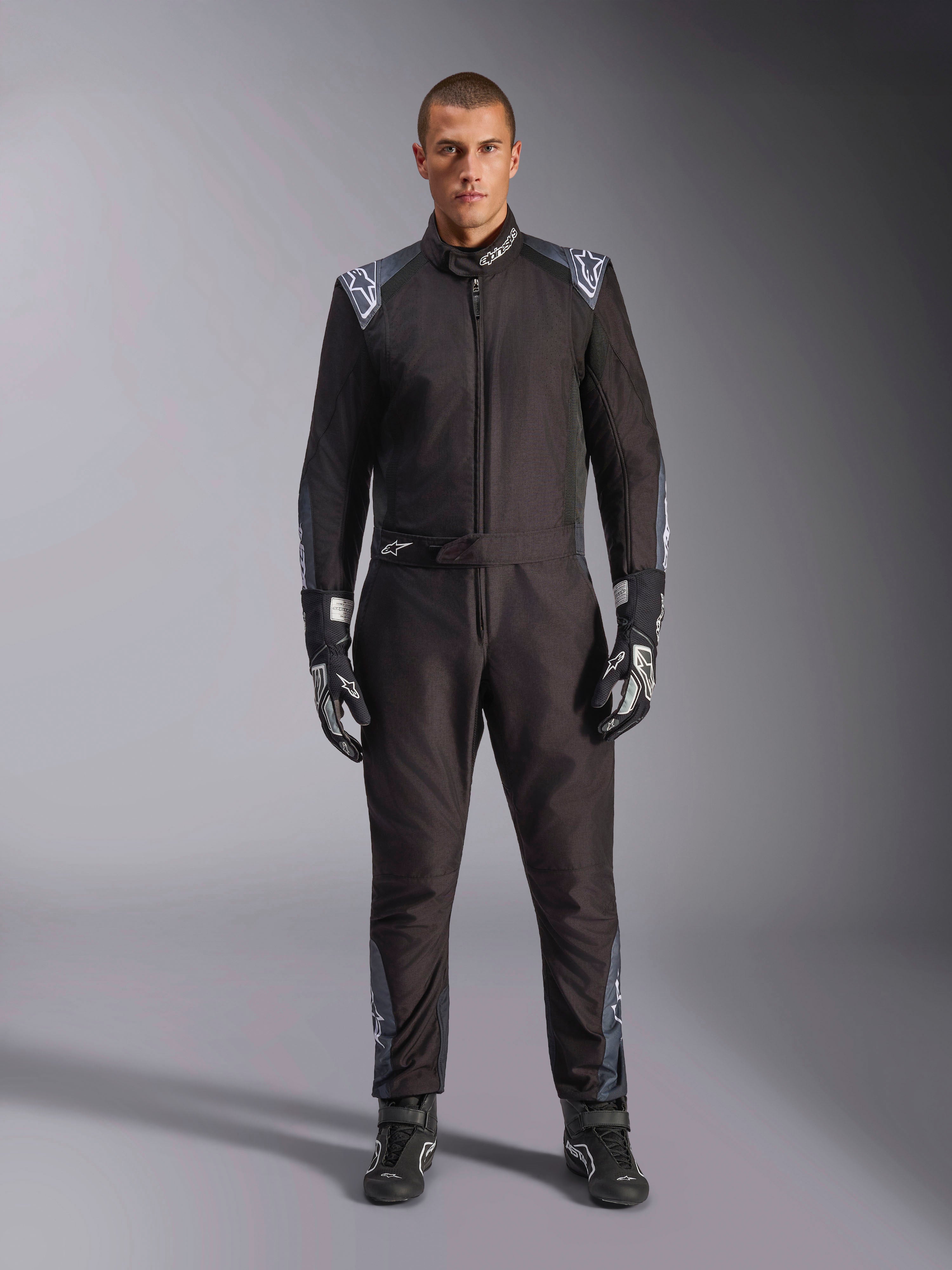 Mono de karting Alpinestars KMX-5 V3, color Negro Dark Shadow, vista de cuerpo completo de un modelo con guantes y botas a juego, con detalles en gris oscuro y logotipos blancos de Alpinestars en los hombros y el cinturón, equipamiento profesional de carreras.