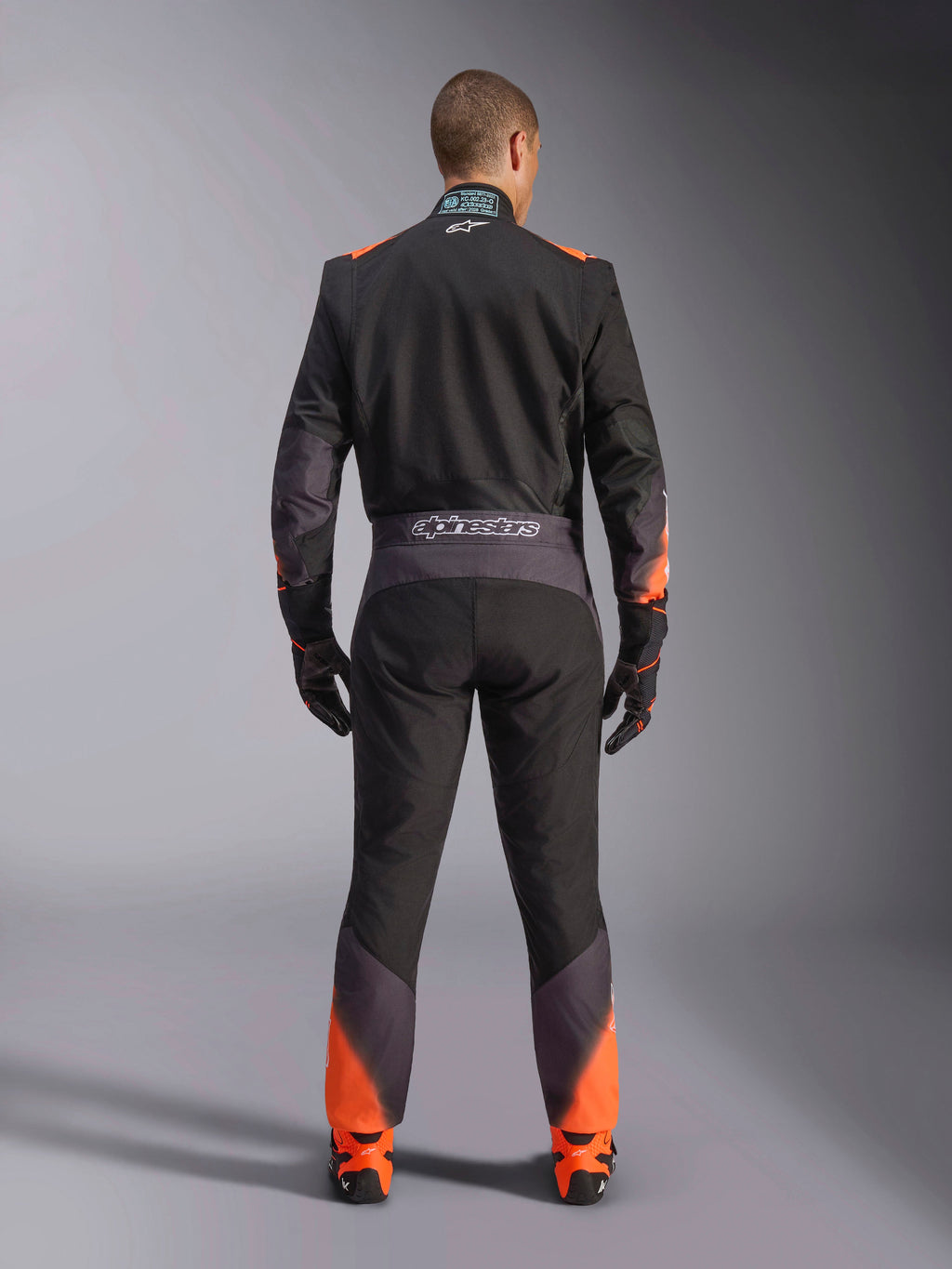 Traje Alpinestars KMX-5 V3, traje de karting para hombre, negro y naranja flúor, con certificación FIA, vista trasera.