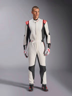 Alpinestars GP Tech V4 Suit, mono de automovilismo de una pieza en blanco, negro y rojo, usado por un modelo masculino con guantes y calzado de competición a juego, con logotipos rojos en los hombros y paneles laterales negros, equipamiento profesional de automovilismo para uso en pista.